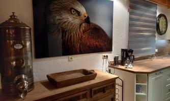 A stylish kitchen with a wooden area and a large wall art of an eagle. On the countertop are some kitchen appliances and a decorative wooden tray.