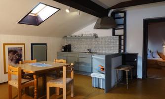 A cozy kitchenette with a wooden dining table and a view of a bright room. The atmosphere is inviting and modern.