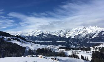 A picturesque winter landscape with snow-covered mountains and cabins. The sky is clear and shines in a beautiful blue.