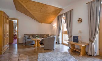 A cozy living room with a wooden ceiling and modern furniture. The windows let in plenty of daylight and create an inviting atmosphere.