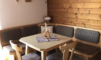 A cozy dining area with a wooden table and comfortable benches. The walls are made of wood, creating a warm atmosphere.