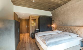 A modern bedroom with a large, comfortable bed and elegant design. The wood and concrete accents create a cozy atmosphere.