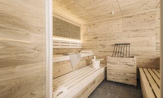 A modern sauna interior with wooden paneling and cozy benches. The atmosphere is relaxing and inviting.