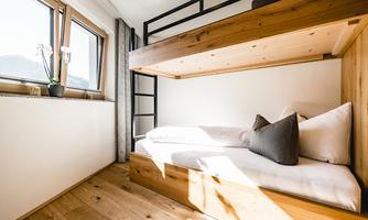 A bright room with a wooden loft bed and a cozy daybed.  
Large windows let in plenty of light and offer a view of the mountains.