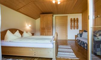 A cozy bedroom with two wooden beds and white pillows. The wooden ceilings and warm tones create an inviting atmosphere.