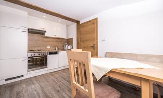 A modern kitchen with a dining table and chairs. The decor is bright and inviting, perfect for a cozy stay.