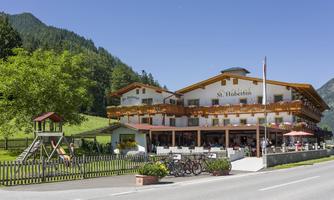 A charming guesthouse with a spacious balcony and outdoor area. The surroundings are green and mountainous, ideal for a relaxing stay.