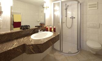 A modern bathroom with a shower cabin and a sink. The walls are light tiled and there are towels on the towel rack.
