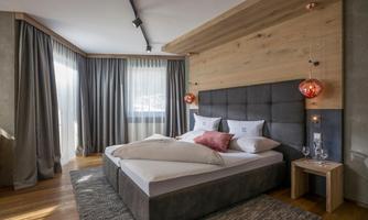 A modern bedroom with a large bed and stylish pendant lights. The bright decor creates a cozy atmosphere.