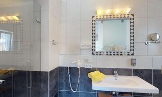 A modern bathroom with an elegant shower and a plain sink. Yellow towels provide a fresh accent.