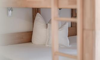 A cozy bed with two white pillows in a wooden frame. The room feels bright and inviting.