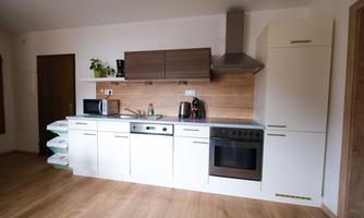 A modern kitchen with white and brown cabinets. It includes a stove, a refrigerator, and a microwave.