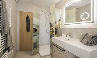 A modern bathroom with a glass shower and a stylish sink. The walls are painted in neutral colors, and there are handy towels.