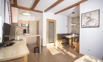 A bright and modern apartment with an open kitchen and a cozy dining area. Wood design and large windows create an inviting atmosphere.