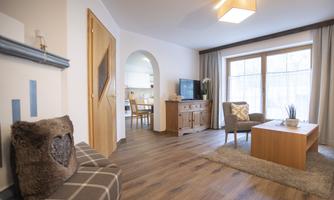 A bright living room with a cozy sofa and a wooden table. Light falls on the room through large windows, creating an inviting atmosphere.