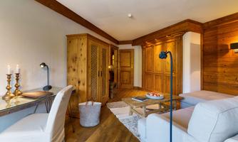 A cozy living space with wooden paneling and a bright sofa. A table with candles and fruit creates an inviting atmosphere.