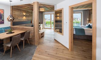 A modern and cozy room with wood decor and a dining table. Through the windows, one looks out at a beautiful view outside.
