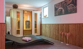 A modern wellness area with a sauna and a lounger. The walls are done in warm wood tones, and there are decorative elements for a relaxing ambiance.