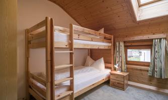 A cozy room with a wooden bunk bed. Large windows provide plenty of daylight and an inviting atmosphere.
