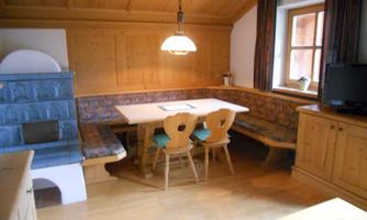 A cozy dining area with wood paneling and a comfortable bench. The room is bright and inviting, perfect for social gatherings.