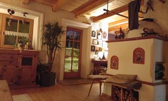 A cozy living space with wooden floors and rustic furniture. Pictures hang on the walls, and a plant brings life to the room.