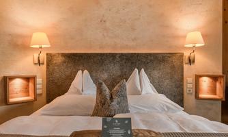 A cozy bedroom with a large double bed and soft lighting. The natural decoration creates a relaxing atmosphere.