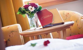 A cozy seating area with two chairs and a table. On the table, there is a bouquet of flowers and a menu.