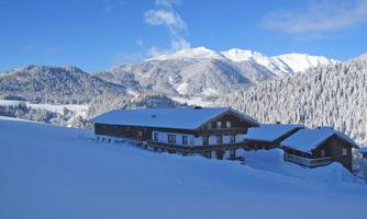 A picturesque winter landscape with snow-covered mountains. In the foreground, there is a cozy chalet.