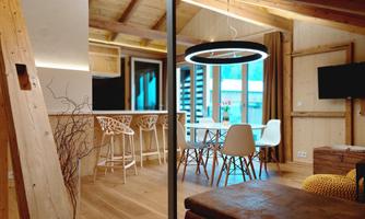 A modern apartment with wood decor and a cozy dining area. Large windows provide plenty of light and a welcoming atmosphere.