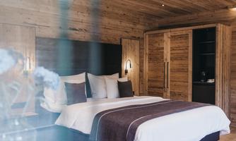 A cozy bedroom with wooden paneling and a large bed. The decor is modern and inviting, ideal for relaxation.