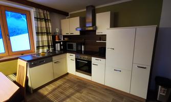 A modern kitchen with bright cabinets and an elegant countertop. It is well equipped with appliances and has a large window that lets in daylight.