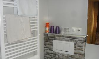 A modern bathroom with towels on a radiator. On the wall, there are soap dispensers and glasses.