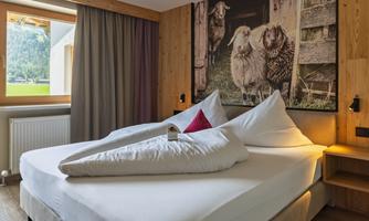 A cozy hotel room with a double bed and a pleasant atmosphere. On the wall hangs a picture of sheep that exudes rural charm.