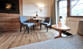 A modern room with two chairs and a small table. Large windows let in plenty of daylight.