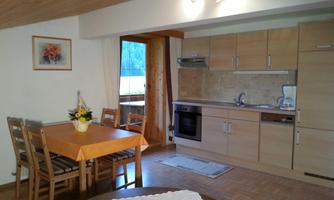 A bright kitchen with modern design and wooden details. There is a dining area with a table and chairs, as well as windows that let in light.