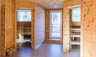 A modern sauna area with wooden paneling. The windows let in a lot of light and provide access to nature.