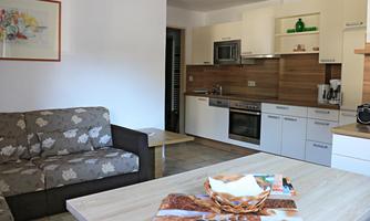 A bright and modern kitchen with a cozy living area. The table is set with a decorative basket and some items.