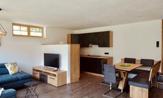 A modern, bright apartment with an open kitchen and dining area. The decor is simple and tasteful with wood and black design.
