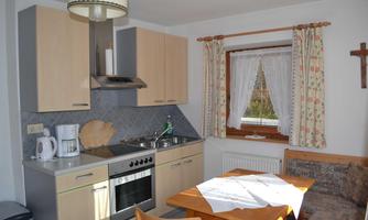 A bright kitchen with modern furniture and a cozy dining area. The window lets in plenty of daylight and the curtains are decorative.
