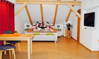A bright and modern room with wooden beams and a cozy bed. A table with chairs and decorative elements enhances the inviting atmosphere.