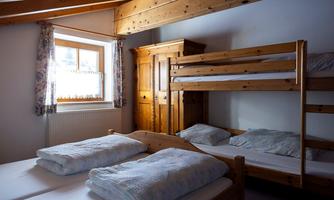 A cozy bedroom with wooden beds and a large window. The decor is simple and inviting, perfect for groups or families.