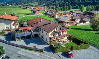 A cozy country house in a picturesque setting. The landscape is green and surrounded by more houses.