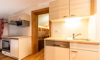 A modern kitchen unit with a stove, a sink, and a dishwasher. The room is designed to be bright and friendly.