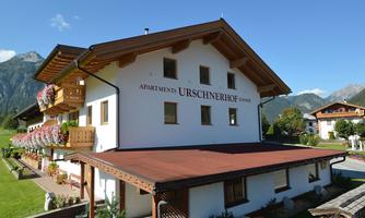 A charming apartment building with wood siding and balconies in a picturesque mountain landscape. The surroundings are green and inviting, ideal for a vacation in nature.