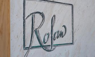 An elegant logo with the name "Rolaw" on a light, textured surface. The font is artistically and elegantly designed.