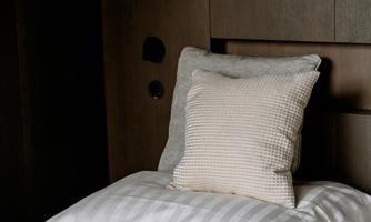 A cozy bed with pillows in neutral colors and a soft blanket. The atmosphere is calm and inviting.