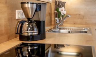 A modern kitchen with a coffee machine and a sink. The wood look creates a warm atmosphere.