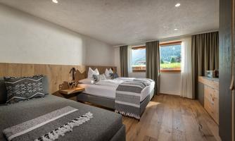 A modern room with two beds and large windows. The wood paneling and cozy design create an inviting atmosphere.