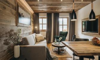A modern living room with wood paneling and a cozy sofa. Large windows let in plenty of light, and the decor is stylish and inviting.