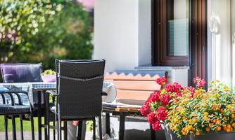 A cozy outdoor area with a table and chairs as well as colorful flowers. The atmosphere is inviting and perfect for relaxing hours outdoors.